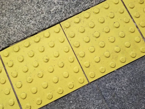 görme bozukluğu olan kişiler için trafik güvenliği. engelli kişilerin serbest dolaşımı için özel ekipman. dokunsal elemanlar ile parlak sarı fayans.