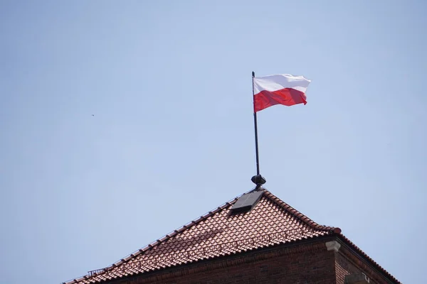 波兰国旗在老城堡的屋顶上对蓝天，老城区，城堡屋顶，旗杆，棕色瓷砖屋顶 — 图库照片