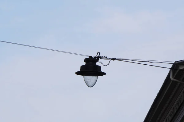 Lanterna entre as casas na rua contra o céu, a rede elétrica da cidade, a luz na cidade, a iluminação pública, a silhueta da lanterna, o contorno da lanterna — Fotografia de Stock