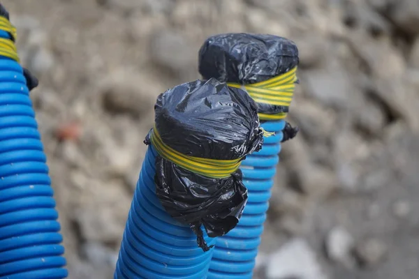 Plastic blue water pipes in the city, wrapped to prevent water from getting inside during the repair. reconstruction, replacement of communications with modern — Stock Photo, Image