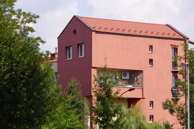 bir mercan cephe ve çit üzerinde saksı çiçekleri ile evde küçük üçgen balkon. Ruhunu dinlendirecek bir yer. birkaç daire için ev, standart dışı mimari