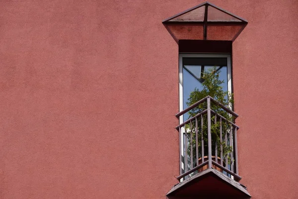 bir mercan cephe ve çit üzerinde saksı çiçekleri ile evde küçük üçgen balkon. ruhunu dinlendirecek bir yer