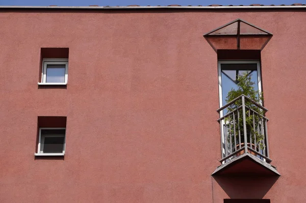 Pequeño balcón triangular en la casa con una fachada de coral y flores en maceta en la cerca. un lugar para descansar tu alma — Foto de Stock