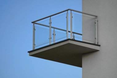 one balcony with glass railing against the blue sky on Sunny day. bottom view, modern building design, Scandinavian style with white walls clipart