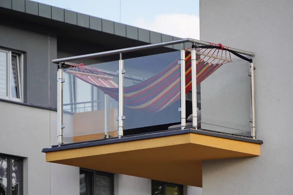 Güneşli bir günde mavi gökyüzüne karşı cam korkuluk ve hamak ile bir balkon. alt görünümü, beyaz duvarları ile İskandinav tarzı. şehirde dinlenme