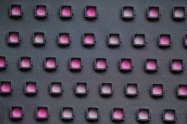 Fekete perforált műanyag, rózsaszín szubsztrát, szimmetrikus térfogatminta — Stock Fotó