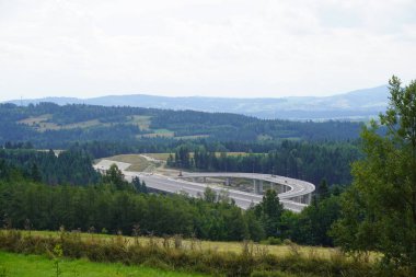 dağlarda modern bir üst geçit inşaatı, dağlık bir alanda yüksek hızlı beton yol, yamaçlarda yüksek ağaçların bir sürü