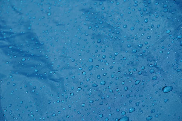 water drops on blue fiber waterproof fabric, background after rain. tent sheet with morning raindrops, Close up the blue background.