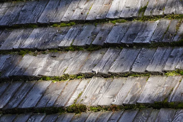 Üzerlerinde yosun olan ahşaptan yapılmış eski bir çatı. Çatı çürüyen, kıymık kenarları ile gri plakalar yapılmış. — Stok fotoğraf