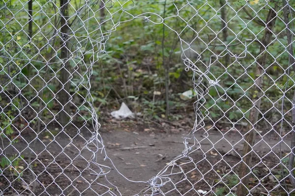 The hole in the steel fence of the mesh netting, the passage to the fenced area illegally. closed terrain for the penetration