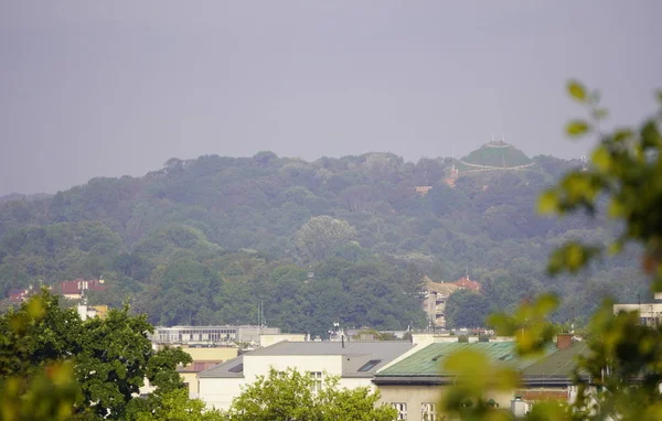 Вид на красочный холмистый город с пышной зеленью летом горного хребта. Жизнь в городе, расположенном между лесистыми холмами, как курорт — стоковое фото