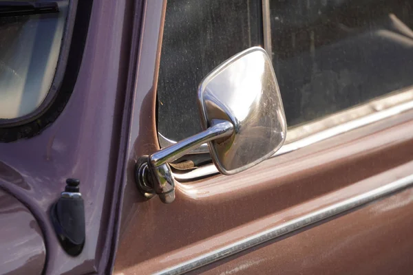 Le miroir d'une petite voiture urbaine rétro dans les rayons du coucher du soleil, après la pluie, le détail extérieur de la vieille voiture, la vieille voiture dans la ville — Photo