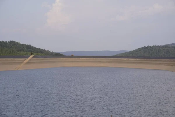 Piscina para fins de fogo no topo da montanha. lagoa artificial com um grande volume de água nele para extinguir o fogo. o trator está na estrada County no topo — Fotografia de Stock