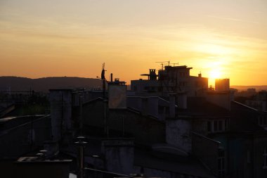 eski sanayi şehrinde gün batımı, kamerada ışık, bulutsuz gökyüzü. gün batımı manzarası, evlerin çatılarında borular ve antenler ile rahat bir akşam
