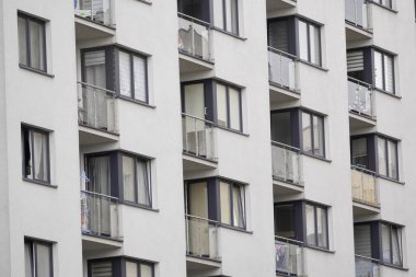 Betondan yapılmış çok katlı bir binanın cam balkonları. Büyük şehirlerdeki insanlar için barınak. Bir apartman kompleksinin Fransız parlaklığı.