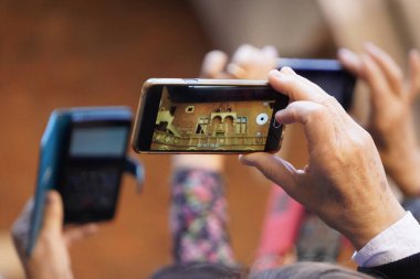Elinde telefonlar, fotoğraflar ve turist çekimleri olan yetişkinlerin elleri. seyahat, tur grupları.