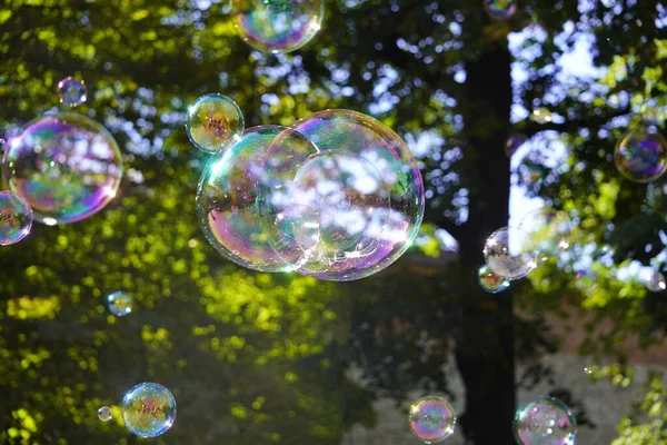 Grandes bolhas de sabão iridescentes de diferentes tamanhos nas ruas da cidade. screensaver, espaço de cópia, fundo . — Fotografia de Stock