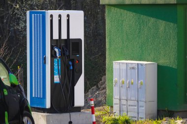 Farklı tipte elektrikli arabalar için şarj istasyonu. Elektrikli araç operasyonu. Park yerinin yakınındaki trafoda elektrikli arabalar var..
