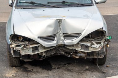 Gri bir yolcu aracının ön kısmı bir kazada ya da trafik kazasında hasar görmüş. Bozuk araba, sigorta ödemeleri. Hasarlı arabaların imhası. Makinelerin tamiri.