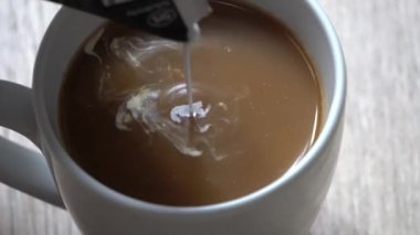 Süt bir fincan kahveye dökülür. Sütlü kahveyle sütlü kahveyi karıştırma süreci. Kahve içeceğim. Sütlü kahve, beyaz kahve..