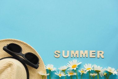 Hasır şapkalı, papatyalı, güneş gözlüklü ve tıbbi maskeli yaz yerleşimi. Seyahat ve eğlence anlayışı. Denize uçuşlar, koronavirüs sırasında dinlenme. Düz mavi üzerine