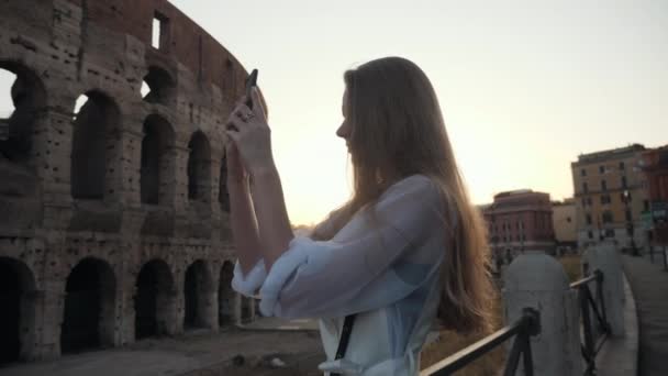 A girl makes a selfie in Rome near the Colosseum.