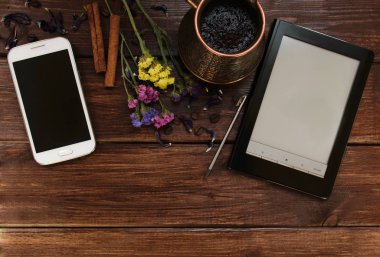 Üstten görünüm Resepsiyon koyu ahşap masa smartphone, ebook, kahve, çiçekler, tarçın ile. Kopya alanı