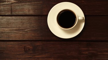 Tahta masa manzaralı bir fincan kahve.