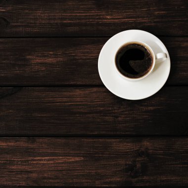 Tahta masa manzaralı bir fincan kahve.