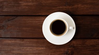 Tahta masa manzaralı bir fincan kahve.