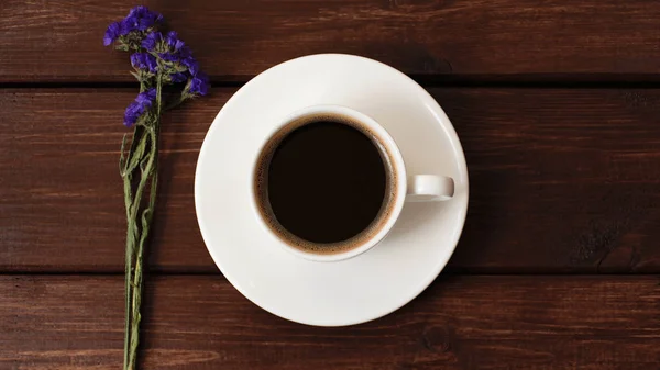 cup of coffee with flowers on a dark wooden table background