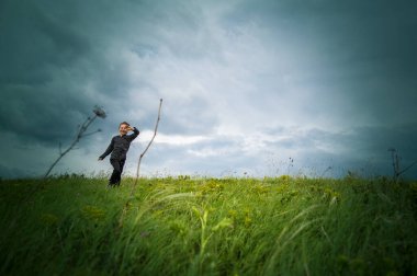 Çocuk arazide koşuyor - yakında yağmur yağacak, rüzgar esiyor, çimenleri büküyor, ama özgür, neşeli ve mutlu.!