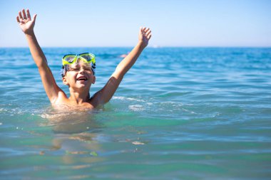 Denizde tüplü dalış bardakları olan bir çocuk yaz güneşinin, tatilin ve yüzmenin tadını çıkarıyor.