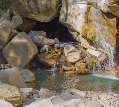 Büyük beyaz taşların arasına bir şelale düşüyor.