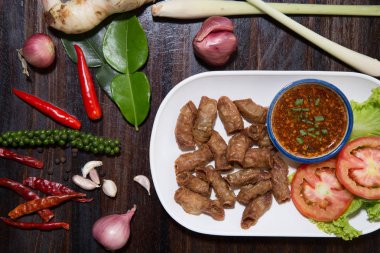 Kızarmış domuz eti ince bağırsak ya da domuz iç organları baharatlı sos ile servis edilir.