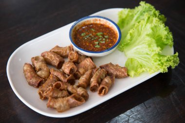 Kızarmış domuz eti ince bağırsak ya da domuz iç organları baharatlı sos ile servis edilir.