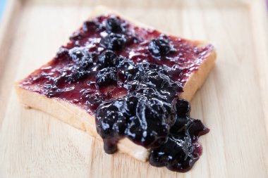 Böğürtlenli reçel. Böğürtlenli reçel sandviç. Ev reçel yaptı. Dilimlenmiş ekmek. Taze yaban mersini. Rustik tarzı. Ahşap masa.