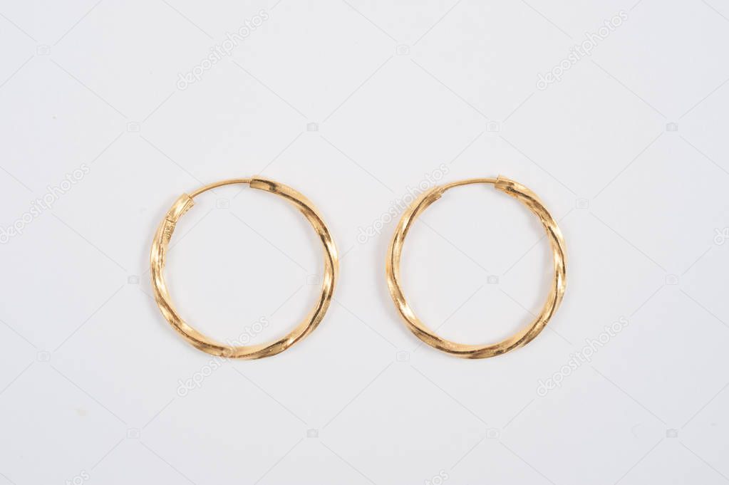  Loop gold earrings on the white background 