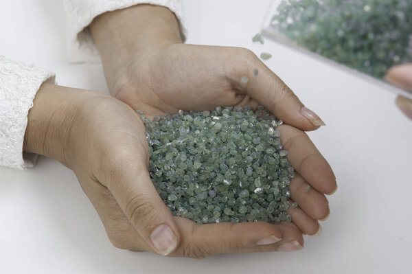 Rough green Peridot gemstone in hand on white background.