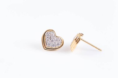 Beyaz zemin üzerinde Kalp şeklinde elmas altın küpe yakın.