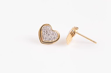 Beyaz zemin üzerinde Kalp şeklinde elmas altın küpe yakın.