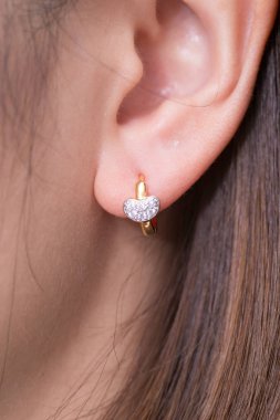 Beyaz zemin üzerinde Kalp şeklinde elmas altın küpe yakın.