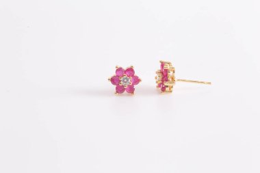 Altın küpe yakut çiçek şekli ile dekore edilmiştir. beyaz arka planda.