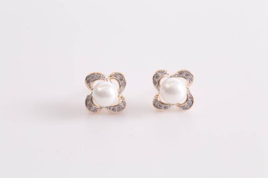 Kulakta elmas ve inci ile kalp şeklinde altın küpe