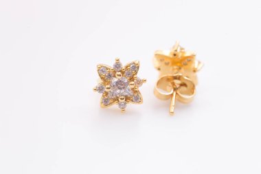 Beyaz arka planda elmas şekilli çiçeklerile altın küpe.