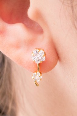 Beyaz arka planda elmas şekilli çiçeklerile altın küpe.