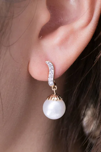 Heart shaped gold earrings with diamonds and pearl at the ear
