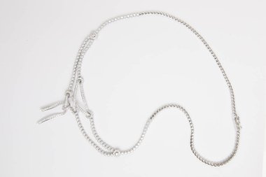 beyaz zemin üzerine gümüş kolye.