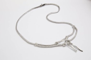 beyaz zemin üzerine gümüş kolye.