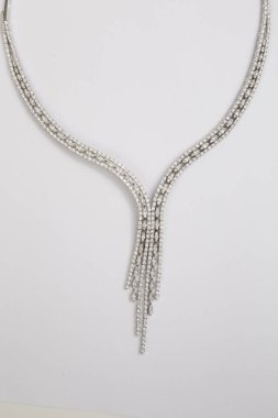 beyaz zemin üzerine gümüş kolye.